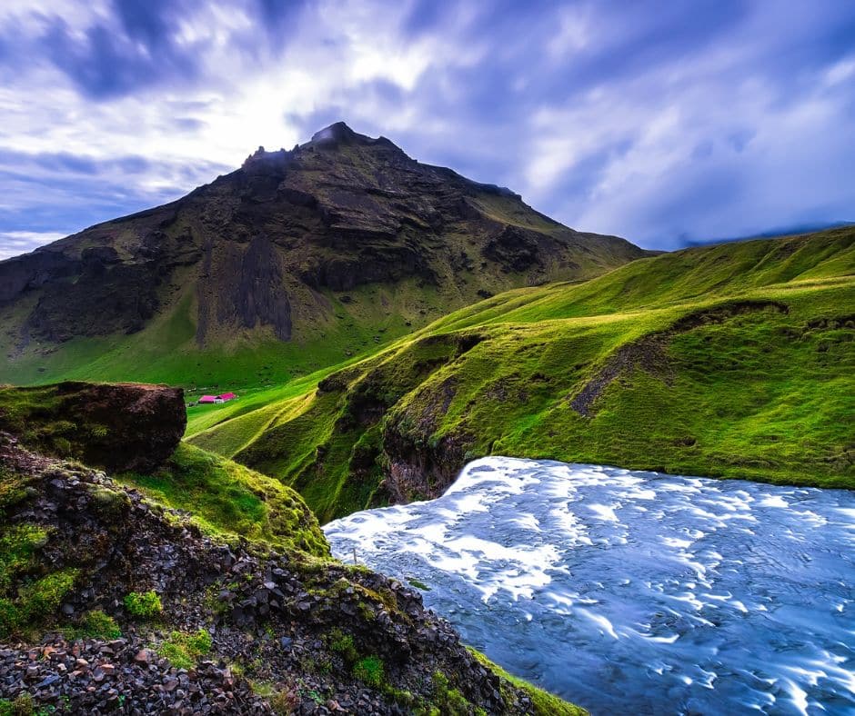 Petit village caché derrière la montagne avec une cascade devant dans notre article 5 jours en Islande : Road trip en dehors des itinéraires classiques #islande #roadtrip #europe