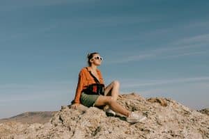 Femme assise sur un rocher qui regarde vers l'avant dans notre article Quand la technologie devient l’allier des femmes seules qui explorent le monde #voyagesolo #voyageaufeminin #applicationsmobiles